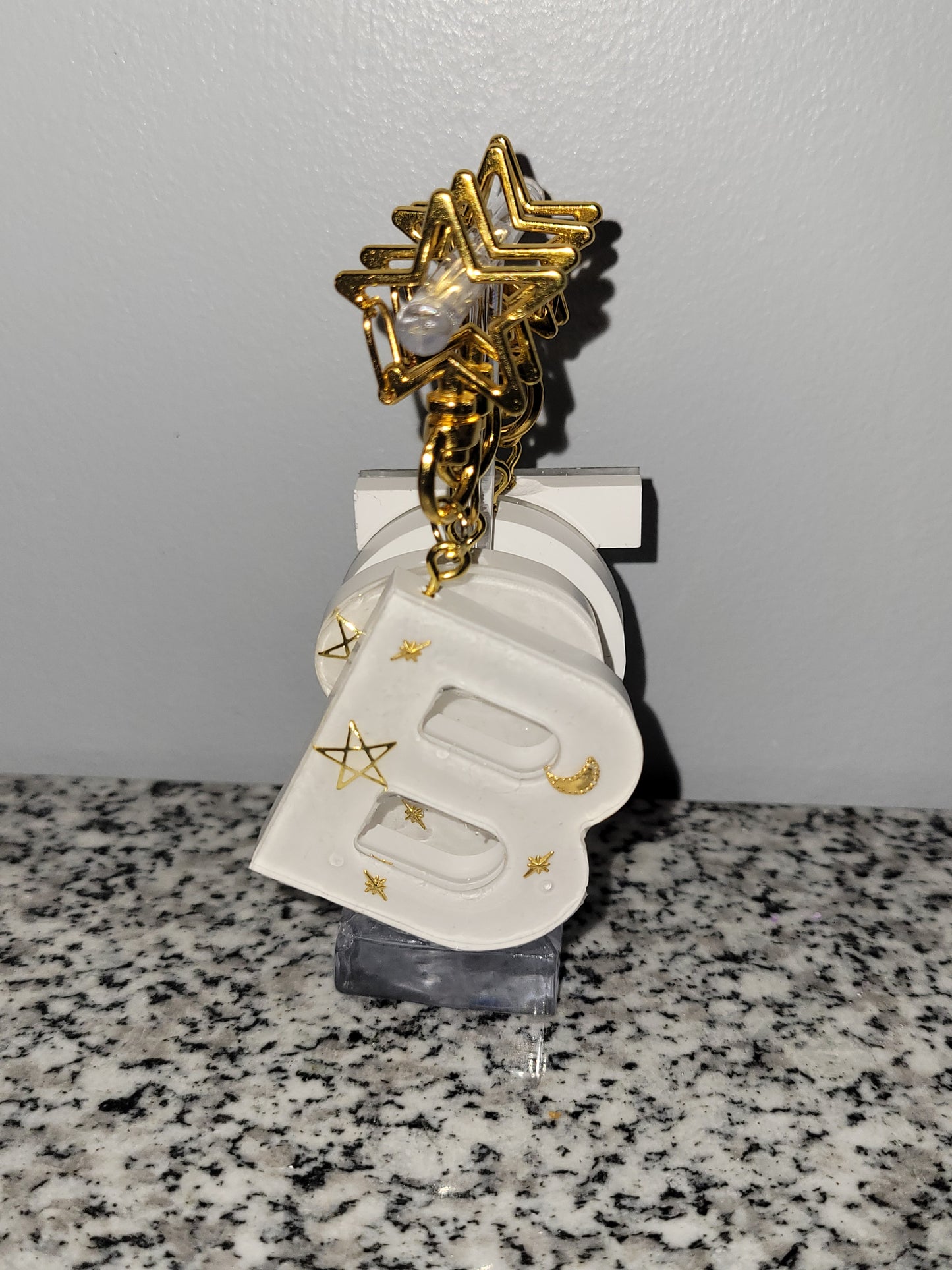 A handmade resin keychain with gold star and moon accents. Pictures is the letter "B"